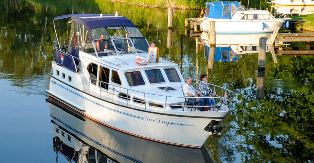 Bugansicht der Pedro Skiron Comfort, Zwei Personen sitzen mit Stühlen auf dem spitz zulaufenden Bug. Eine Person sitze auf dem Dach des Bootes und eine weitere Person steht am Steuer auf dem Achterdeck.