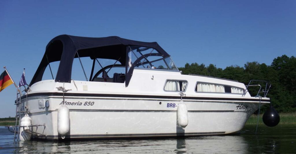 Außenansicht der Almeria 850, ein weißes Boot mit schwarzen Akzenten und Blauem Cabrio-Verdeck